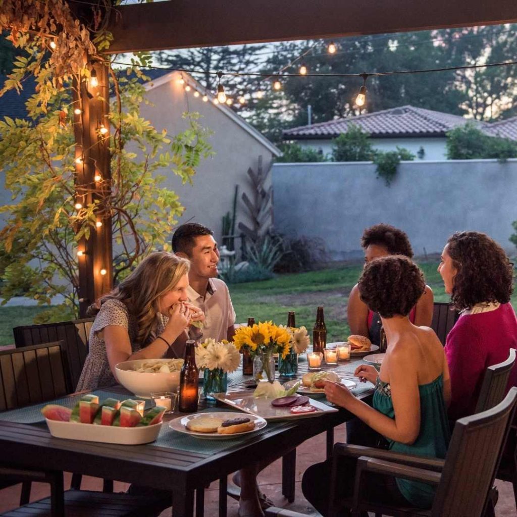 Fairy lights outside hanging above a group of people during a party